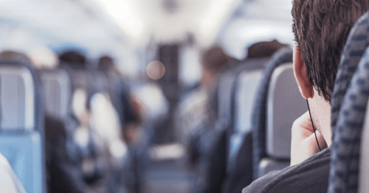 Person seated in an airplane aisle seat, exemplifying strategic seating choice for easy movement and stretching to alleviate sciatica discomfort during travel.